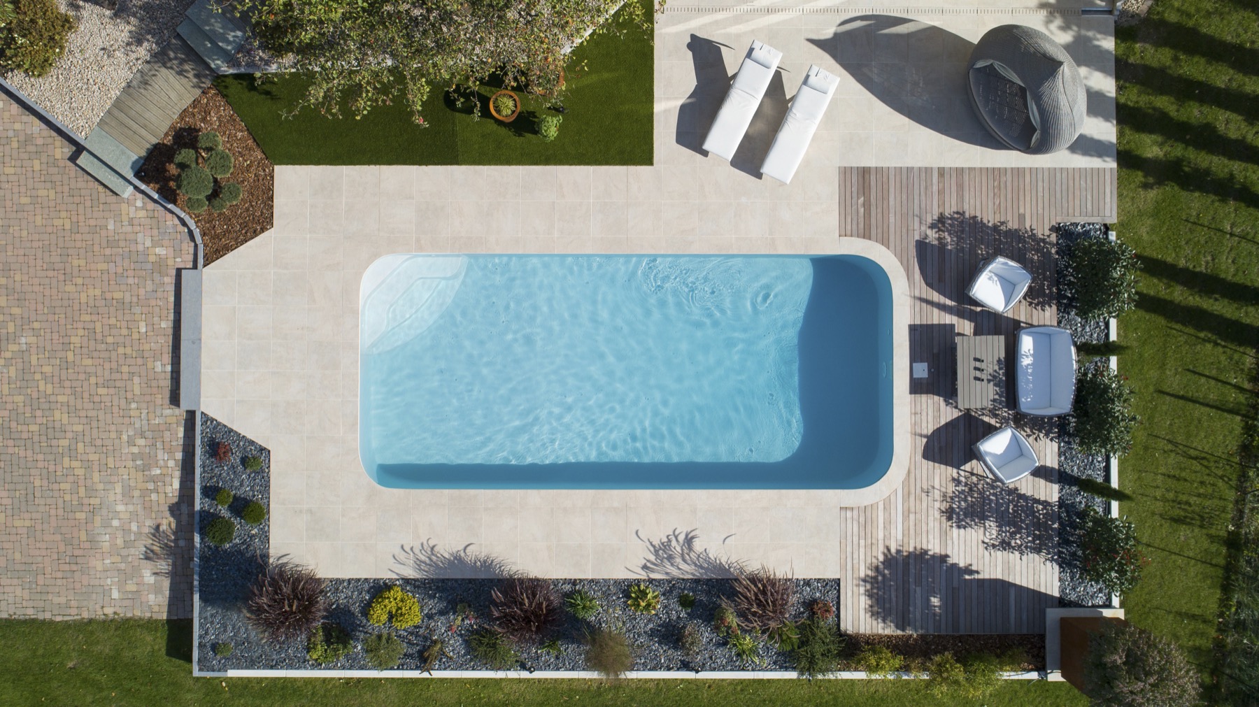 Rechteckiger Pool aus der Vogelperspektive mit Terrasse und Garten